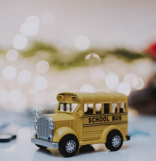 Photograph of a toy school bus with twinkle lights blurred in the background